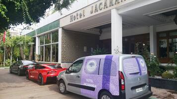 Hotel Jacaranda features a distinctive entrance with its name prominently displayed above a parking area and decorative facade.