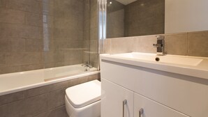 Une salle de bain moderne avec une douche à parois de verre, un lavabo blanc et des toilettes.