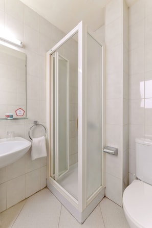 A bathroom with a glass-enclosed shower, a white sink, and a toilet.