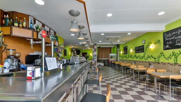 Un restaurant doté d’un bar, d’un sol à carreaux et de murs verts.