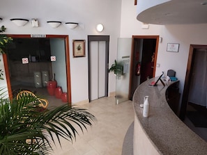 A reception area with a counter, a framed certificate on the wall, and a door marked "CAFETERIA".