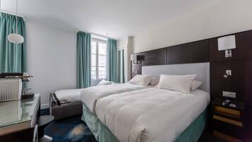 A hotel room with a large bed, a desk, a chair, a lamp, and a window with curtains.