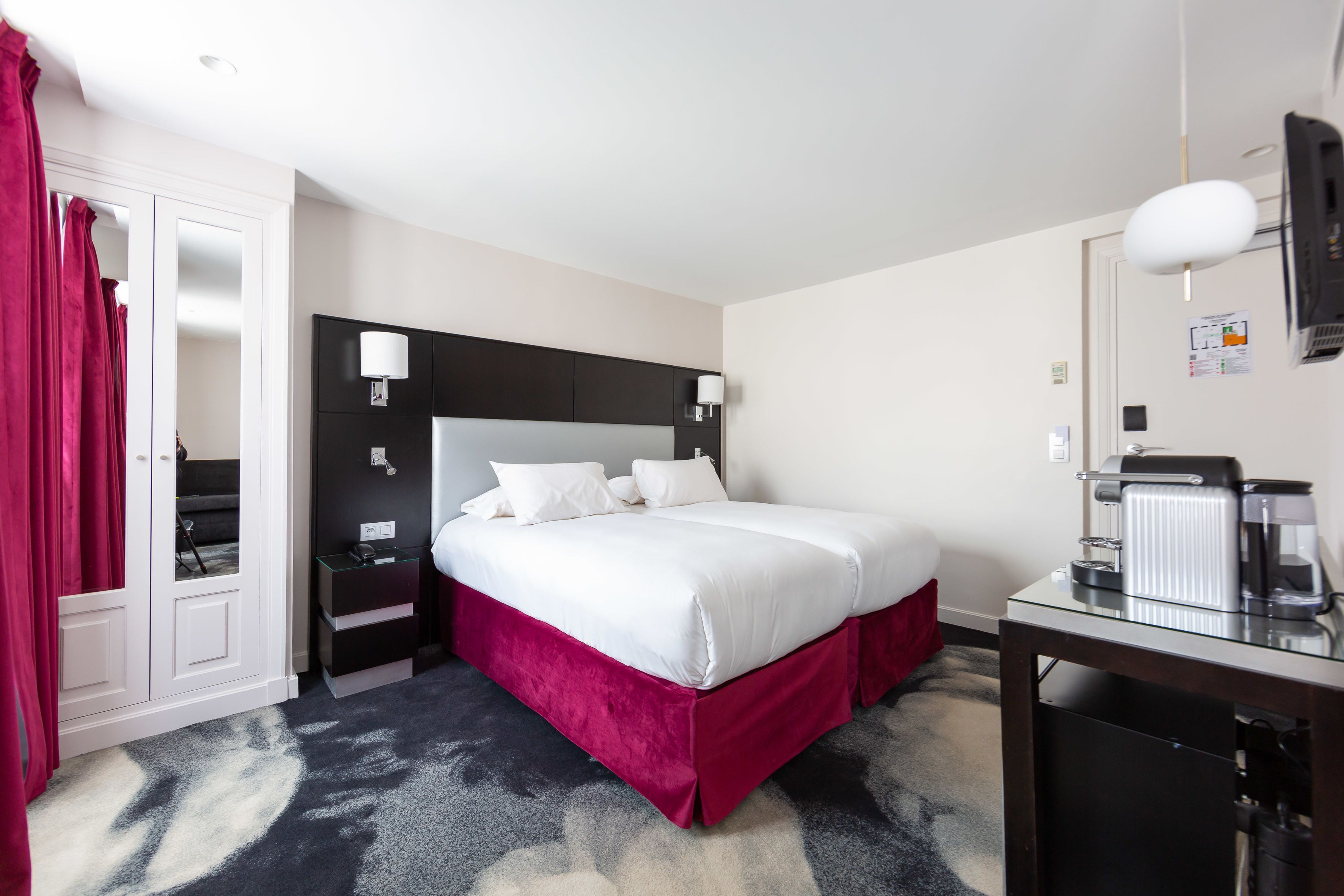 Una habitación de hotel con una cama grande, un escritorio con cafetera y un armario.