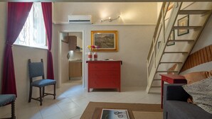 Un espacio habitable compacto con una escalera, un aparador rojo, un sofá y una zona de comedor.