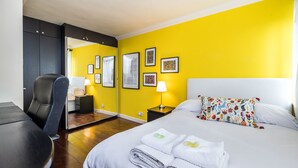 A hotel room with a bed, a desk, a chair, and a mirror. - Fitzrovia Apartments by Allô Housing (London)