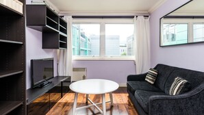 A modern living room with a white round table, dark sofa, and built-in shelving. - Fitzrovia Apartments by Allô Housing (London)