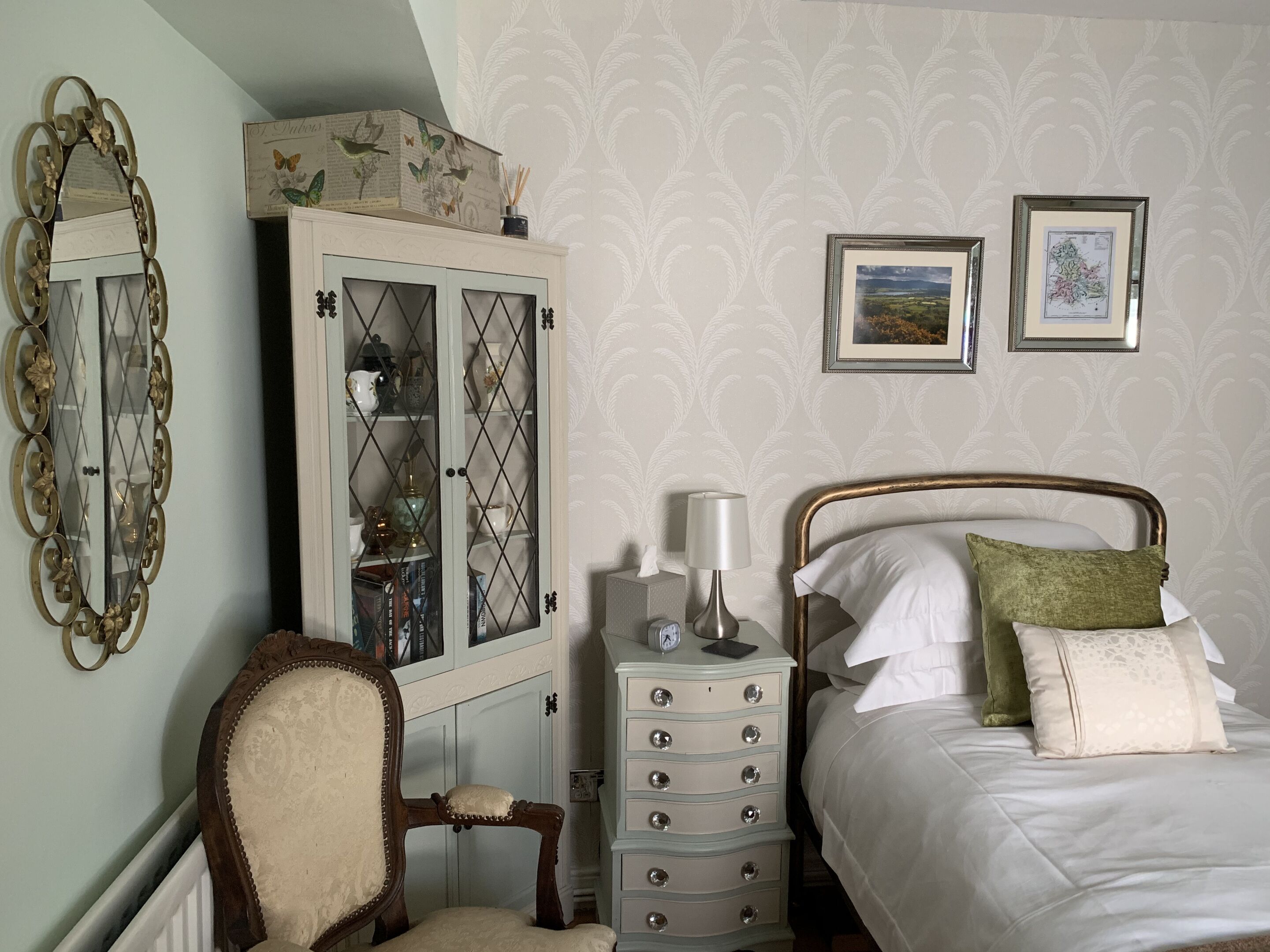 A bedroom with a bed, a dresser, a chair, a cabinet, and two framed pictures on the wall.