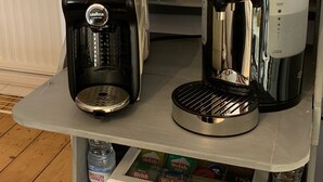 Dos cafeteras sobre una mesa con una botella de agua y una caja de té gales.
