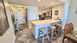 A kitchen with a central island, bar stools, a refrigerator, and a microwave. - Relax and Catch a couple fish! 🎣 ~ There is something for everyone! (Gulf Shores)