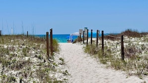 A sandy beach path leading to a beach area with a blue umbrella and a sign. - Relax and Catch a couple fish! 🎣 ~ There is something for everyone! (Gulf Shores)