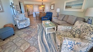 A living room with patterned furniture, a dining area, and a kitchen in the background. - Relax and Catch a couple fish! 🎣 ~ There is something for everyone! (Gulf Shores)