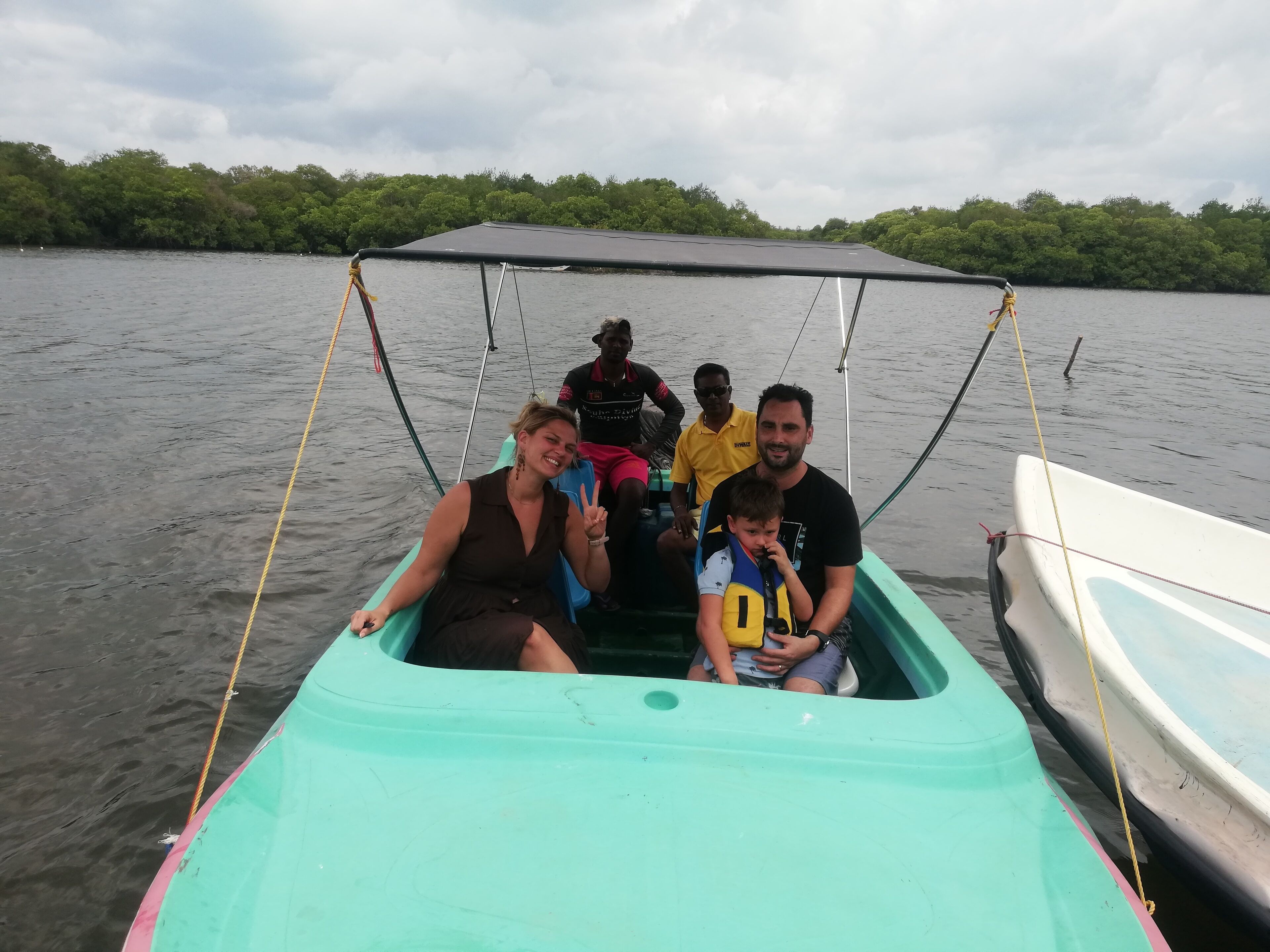 A boat with a canopy, passengers, and a calm water body.