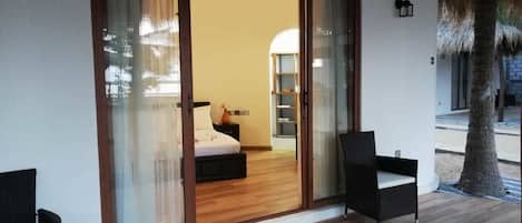 Una habitación con una cama, una mesita de noche, una silla y un ventanal amplio.