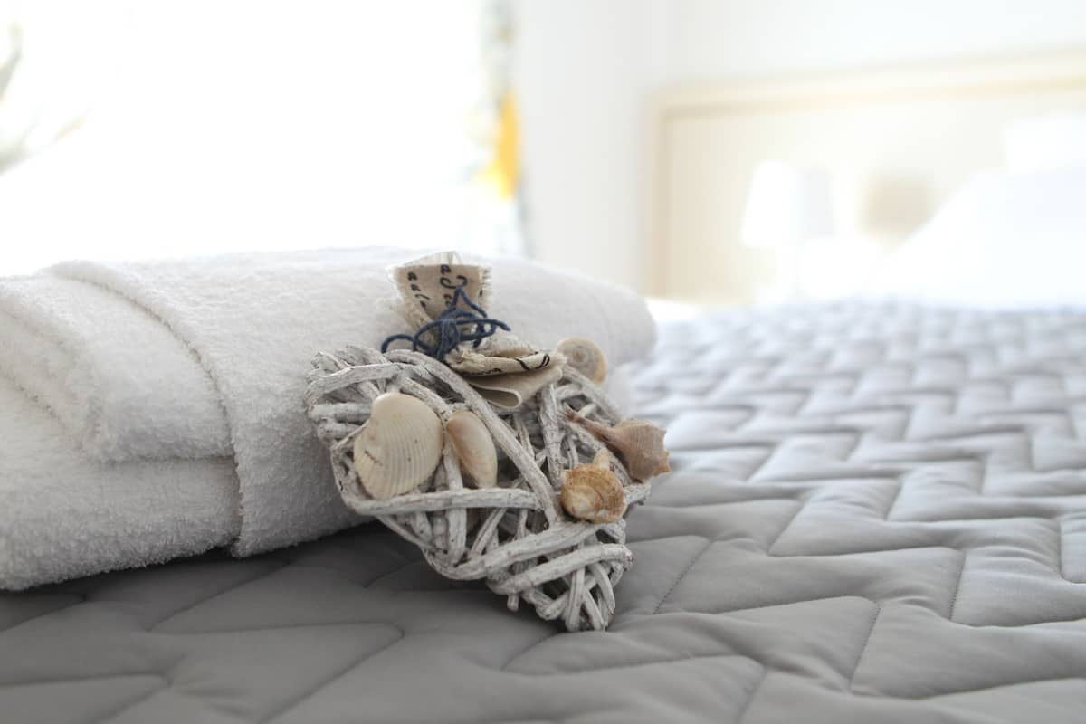 A neatly folded white towel on a gray quilted bedspread.