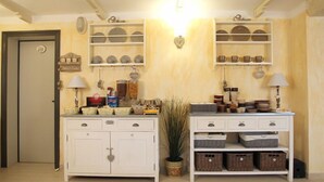 Une cuisine avec des meubles blancs, des étagères remplies de vaisselle et une plante en pot.