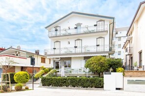 A two-story building with a balcony on the upper floor, a visible entrance, and a small outdoor seating area. - Hotel Il Nido (Rimini)