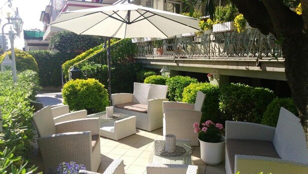 Un espace extérieur aménagé avec des meubles en osier, un grand parasol et des plantes en pot.