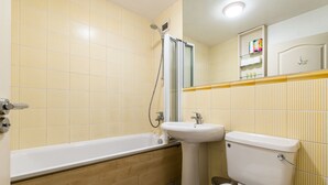 Un baño con bañera, lavamanos e inodoro.