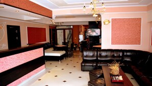 Una hall d'albergo con reception, area salotto e televisore.