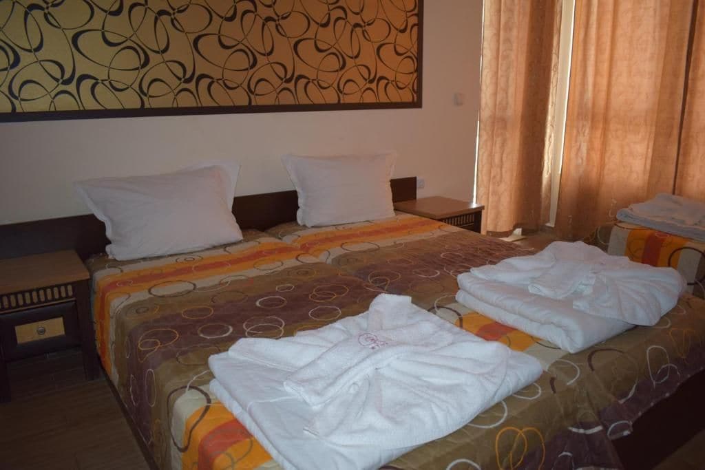 A hotel room with a bed, two pillows, a bedside table, and a wall art piece.