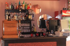 A bar area with shelves of liquor bottles, glasses, and a Coca-Cola vending machine. - Ryor (Nessebar)