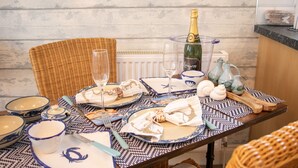 Una mesa de comedor dispuesta con vajilla de diseño azul y blanco, una botella de champán y conchas decorativas.