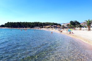 A beach with clear water, sandy shore, and beach umbrellas. - New family apartment with terrace 4+2 (Povljana)