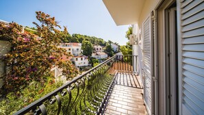 Ein Balkon mit Metallgeländer, der auf ein Wohngebiet mit Häusern und Grünflächen blickt.