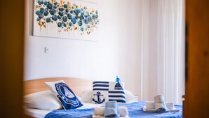 Ein Hotelzimmer mit einem Bett, einem Blumenbild und Kissen im maritimen Stil.