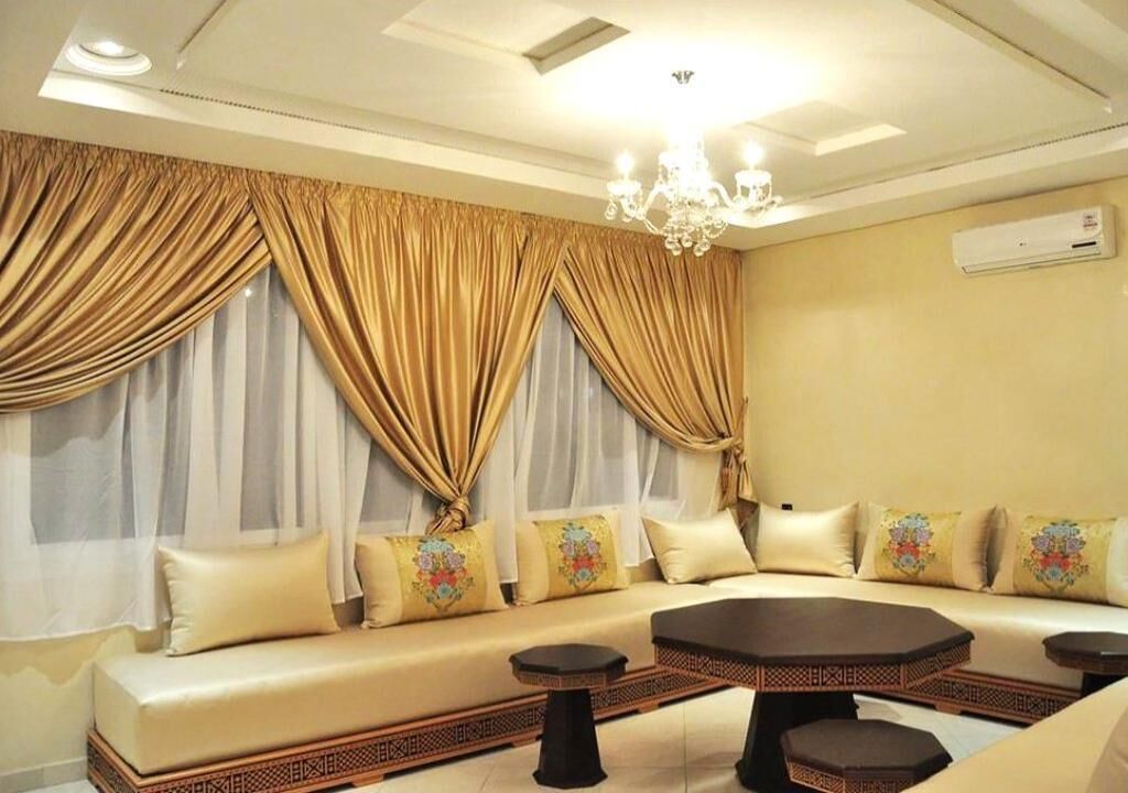 A room with a sofa set, a coffee table, and a chandelier.