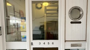 A white door with the number 3456, a round window, and a plaque below it. - Pebbles. The Beach House, apartment in central Eastbourne with private parking (Eastbourne)
