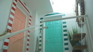 A staircase with a handrail leading to a turquoise door, adjacent to a peach-colored door. - Pebbles. The Beach House, apartment in central Eastbourne with private parking (Eastbourne)