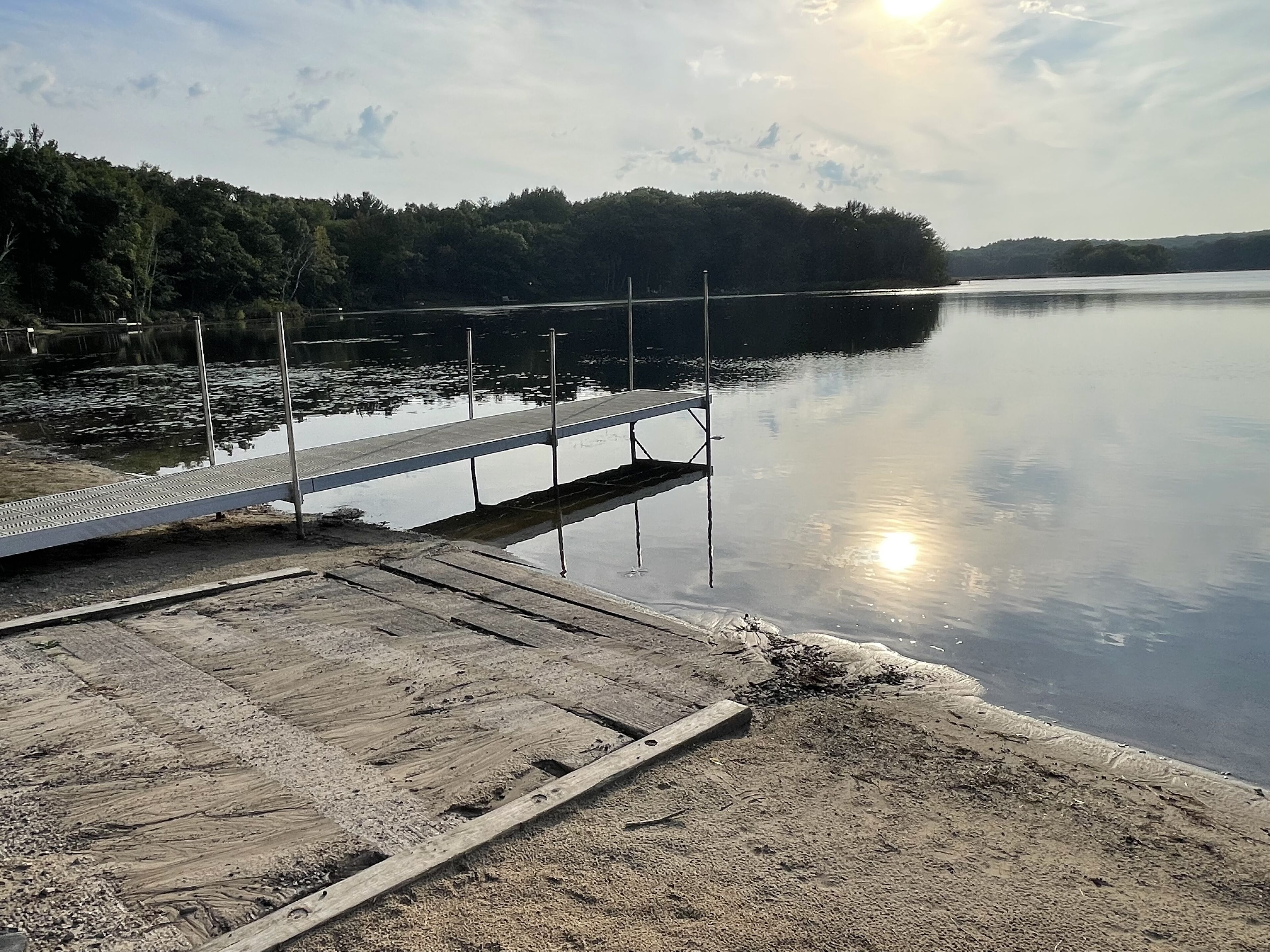 A wooden dock extending into calm water, surrounded by a forested area.