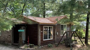 A rustic cabin with a metal roof, a wooden porch, and a swing set. - WI Dells- full Rec lake,swim,boat,ski,UTV,fish,BBQ,sauna,fire pit,hiking,kayak (Oxford)