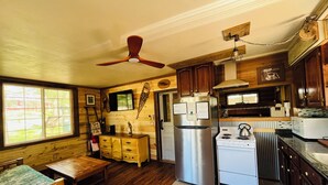 A compact kitchen with wooden cabinets, a stainless steel refrigerator, a stove, and a ceiling fan. - WI Dells- full Rec lake,swim,boat,ski,UTV,fish,BBQ,sauna,fire pit,hiking,kayak (Oxford)