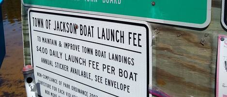 Un panneau vert avec du texte blanc indiquant les règles applicables aux embarcations et le montant des frais de mise à l’eau des bateaux.