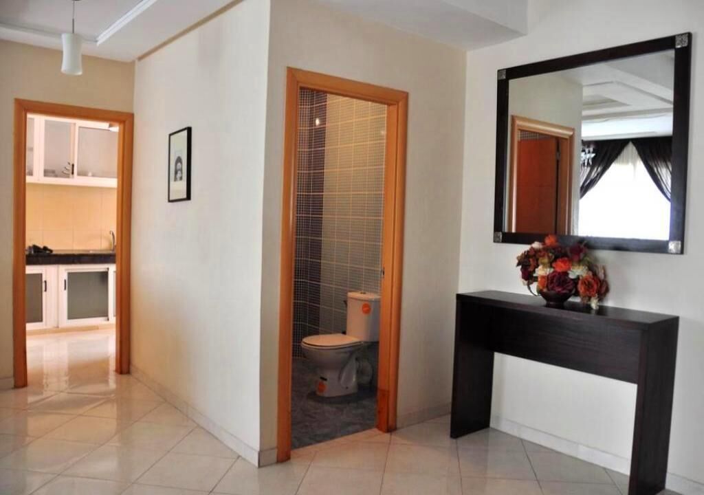 A modern bathroom with a toilet, a vanity with a mirror, and a small sink.