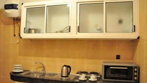 Une cuisine avec des meubles blancs, un plan de travail noir, une bouilloire, un grille-pain et un évier.