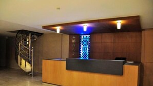Un comptoir d’accueil avec un revêtement en bois, un élément décoratif mural bleu illuminé et un escalier en colimaçon en arrière-plan.