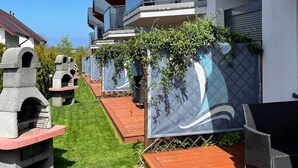 Un barrio residencial moderno con varias casas que tienen balcones, una terraza de madera y una parrilla de piedra.