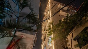A nighttime street view with a building featuring a neon sign, a palm tree, and overhead power lines. - Khach San Sao (Hanoi)