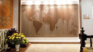 A reception area with a wooden slat partition, a vase of yellow flowers, and a traditional decorative piece. - Khach San Sao (Hanoi)