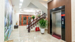 A hotel lobby with a marble floor, a staircase, a large potted plant, and an elevator. - Khach San Sao (Hanoi)
