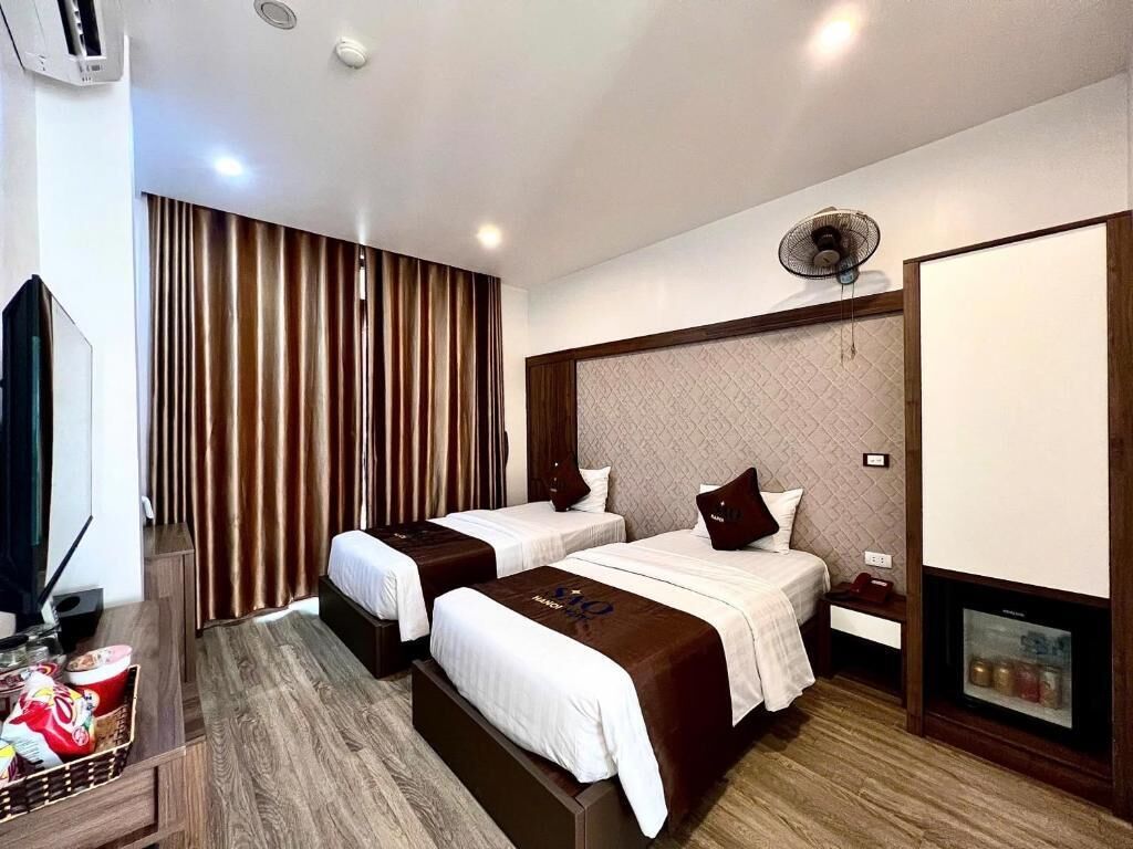Habitació d'hotel amb dos llits, televisió, xemeneia i un mur degassat.