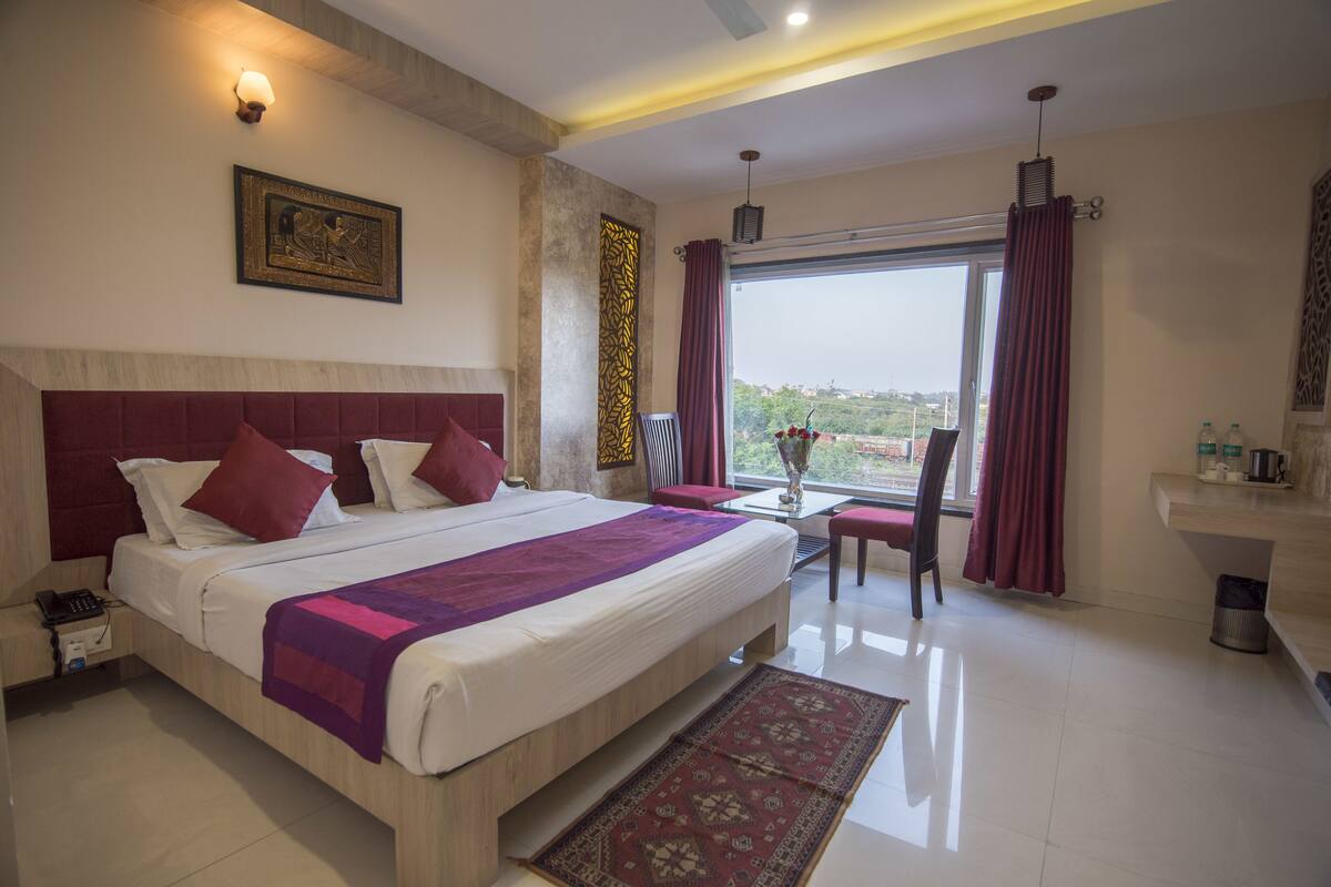 Quarto de hotel com uma cama grande, uma escrivaninha e vista para a cidade.