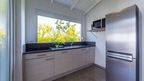 A modern kitchen with a stainless steel refrigerator, a microwave, and a window with a view of palm trees. - ♥ Perfect Family Getaway ♥ with Tropical Pool & Garden (Willemstad)