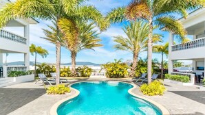 A pool surrounded by palm trees and lounge chairs, with a view of mountains in the background. - ♥ Perfect Family Getaway ♥ with Tropical Pool & Garden (Willemstad)