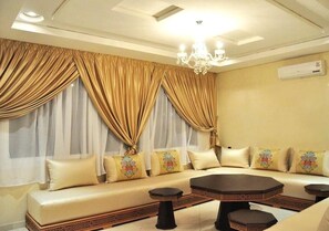 A room with a sofa set, a round coffee table, and a chandelier.