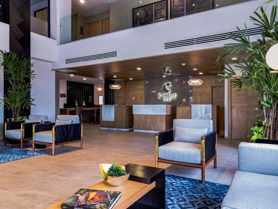 Un vestíbul d'hotel modern amb zones d'seure, una recepció i una pantalla gran que mostra el nom de l'hotel.