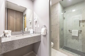 Ein modernes Badezimmer mit Marmorwaschtisch, einer Duschkabine aus Glas und einem hölzernen Waschtischunterschrank.
